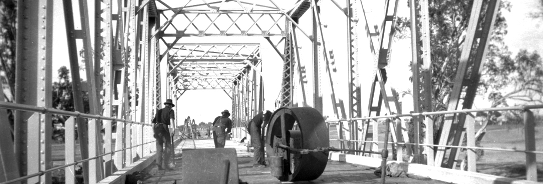 Black and white photo of men making road surface on bridge