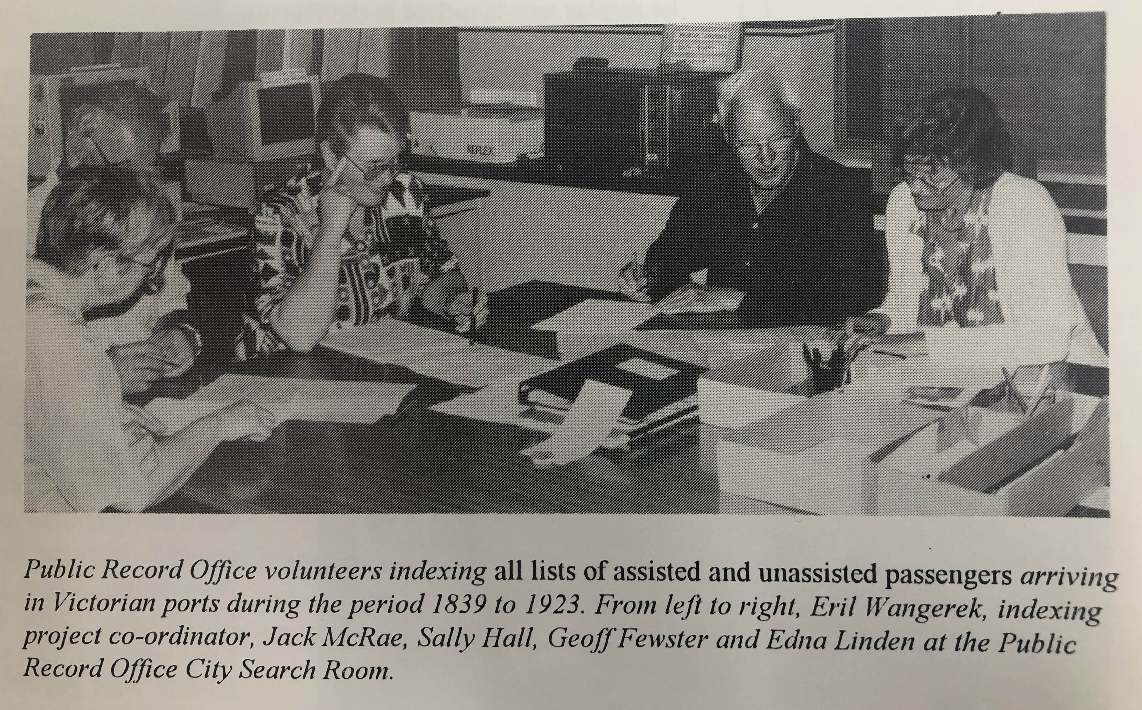 black and white photo of volunteers at a desk looking over documents