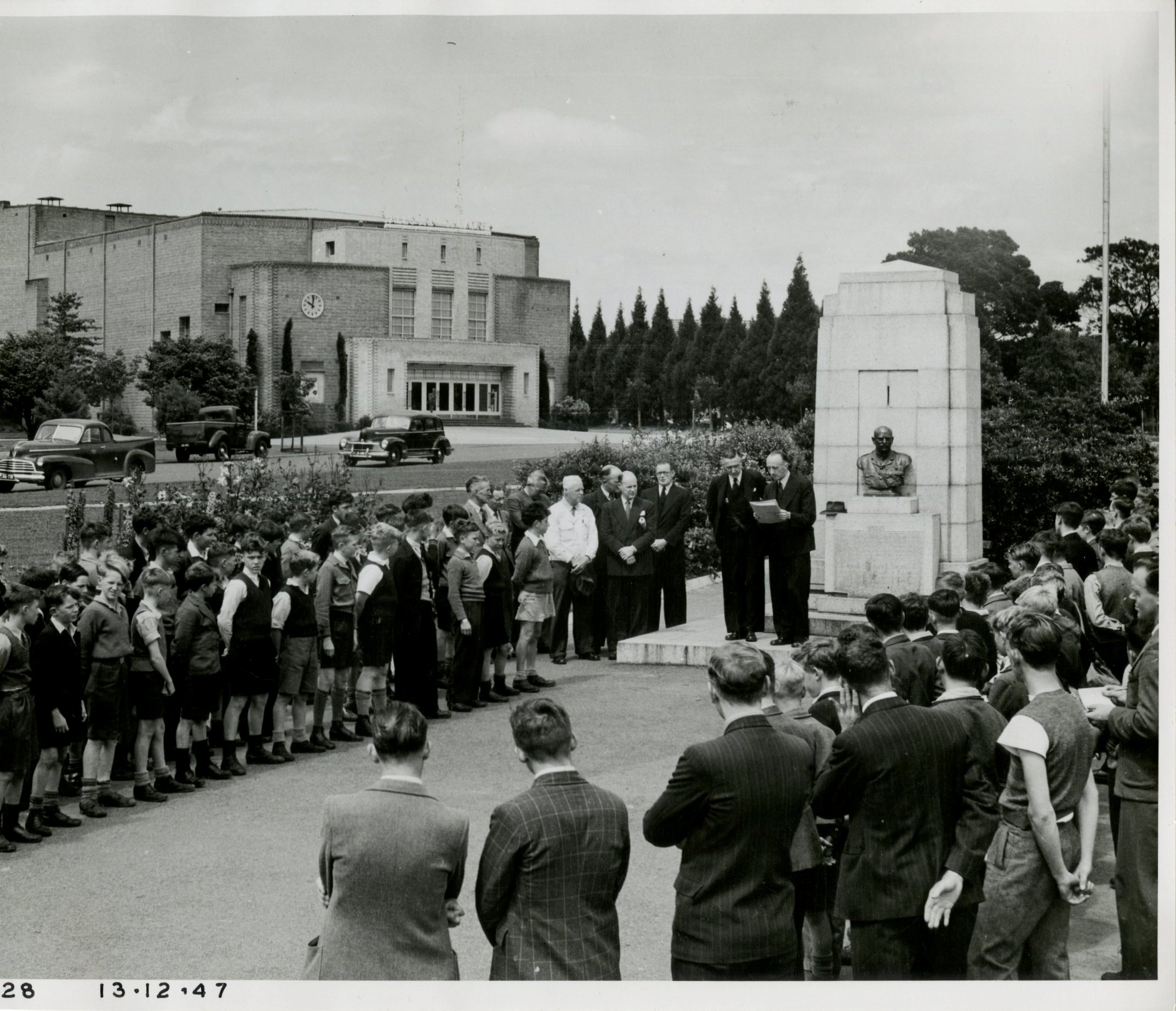 Crowd of men and school boys listening to a speech at a memorial