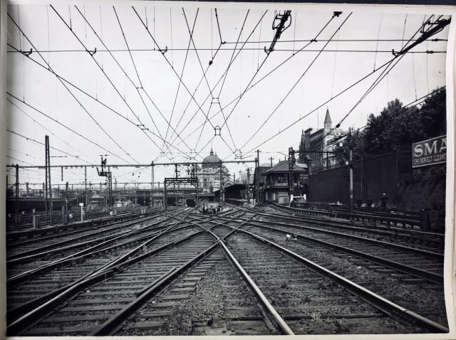 black and white photo of tracks in the foreground and flinders street station in the back