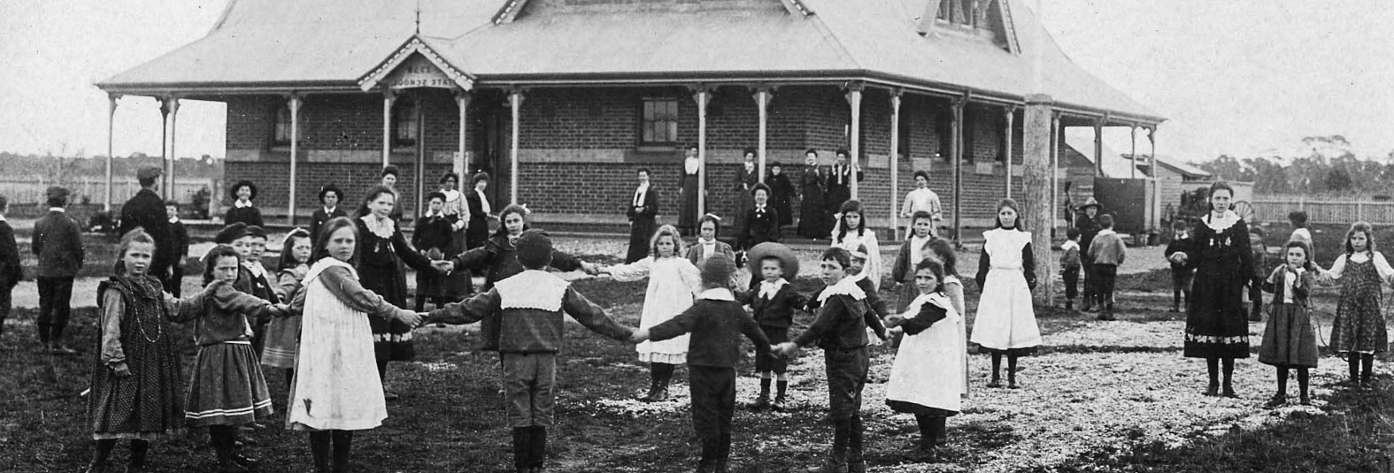 Black and white photo, children playing outside of a school