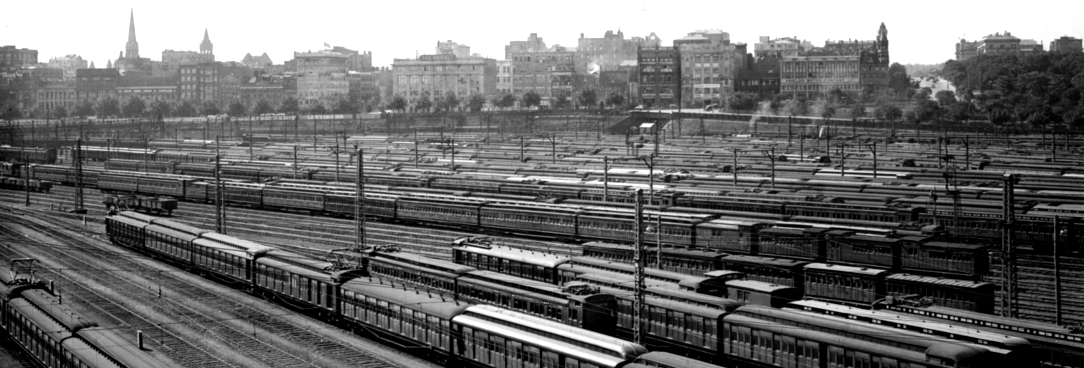 Black and white photo of trains in city rail yard