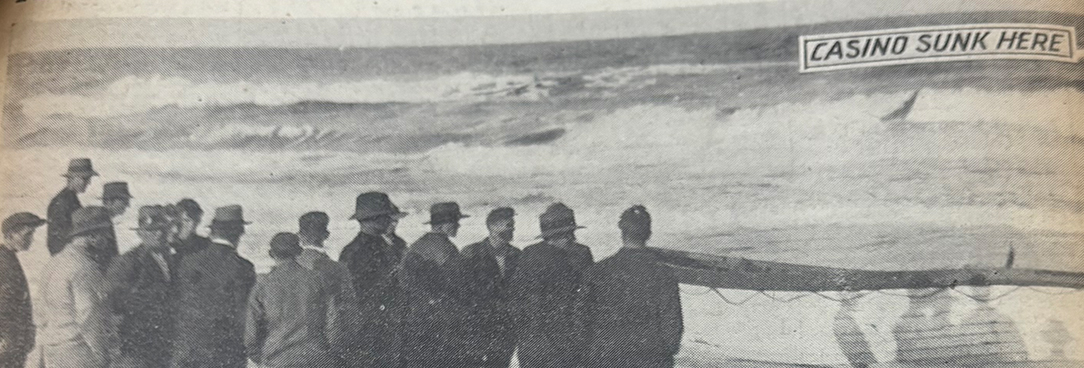 a crowd gathers at the water's edge to view the wreckage of the SS Casino