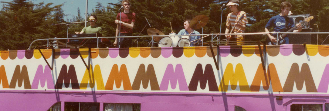 colourful photo of a band playing on top of a Big M branded pink bus