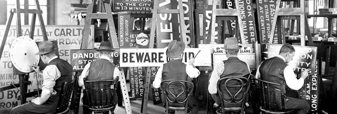 black and white photo of men painting signs
