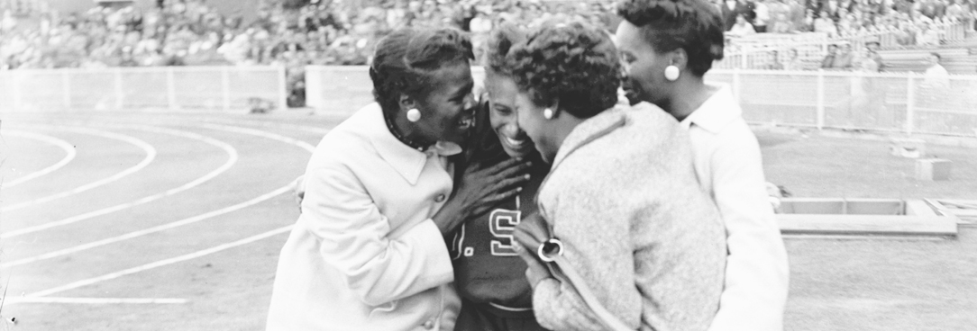 black and white photo of women hugging on a race track after a winning race