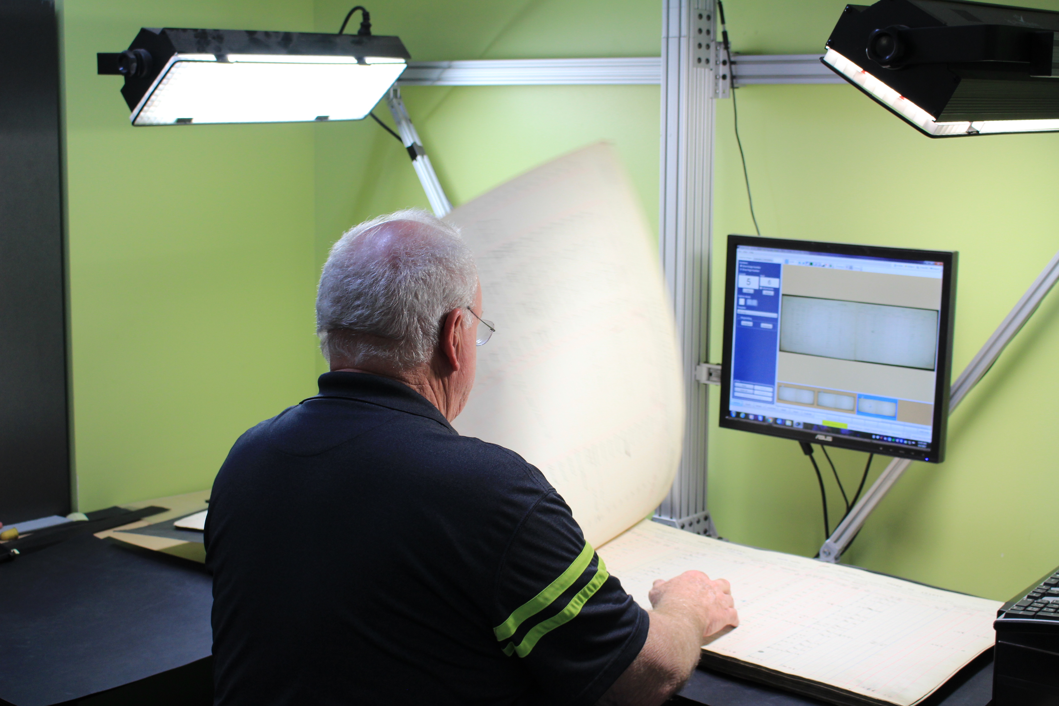 Photo of a man photographing a rate book using special scanning equipment