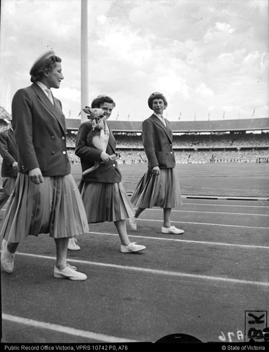 A photo of female athletes walking around the MCG with a toy kangaroo in their arms