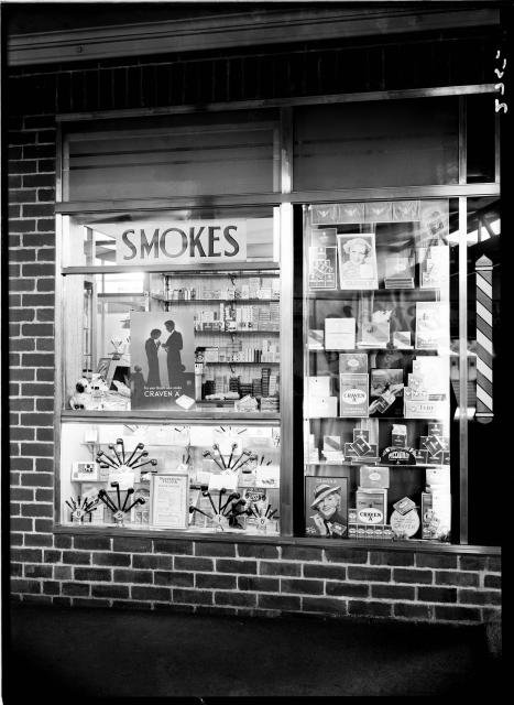 black and white photo of a kiosk selling smokes