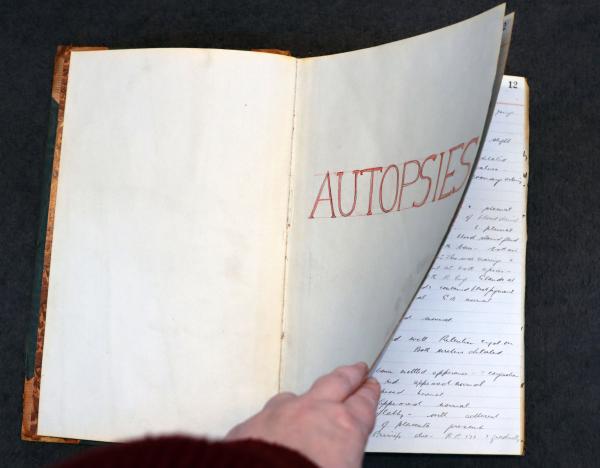 a book labeled autopsies being flipped through 