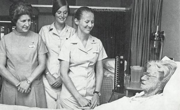 nurses looking over a woman as she lays in a hospital bed