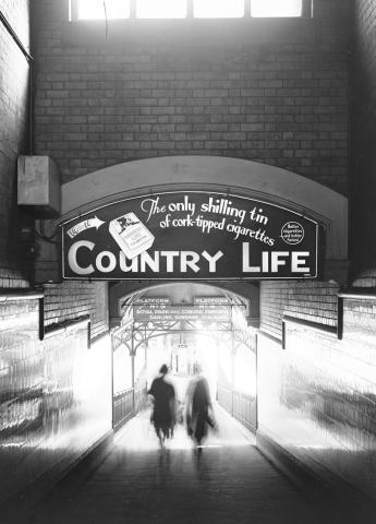 black and white photo of two shadowy figures walking down a train platform