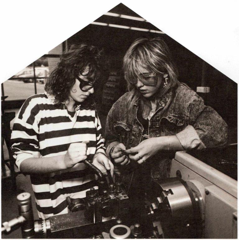 Black and white photograph of two high school students adjusting a large piece of machinery with a spanner