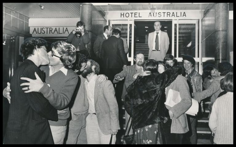Black and white photograph of same sex couples kissing outside the Hotel Australia as part of a protest